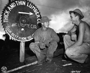 Pvt. Arthur Ristinen of Menagha, Minn., and Pfc. John Weinzinger of Phillips, Wisconsin, 186th Inf. Reg., 41st Inf. Div., relax in front of Warisota Plantation sawmill run by men of the 186th. Sawmill was used to obtain lumber for bridge construction on the new Oro Bay Dobodura road, New Guinea. (5 May 43) Signal Corps Photo: GHQ SWPA SC 43 5816 (T/4 Harold Newman)
